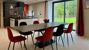 Eine moderne Küche mit Essbereich, großen Fenstern und einer außergewöhnlichen Pendelleuchte.