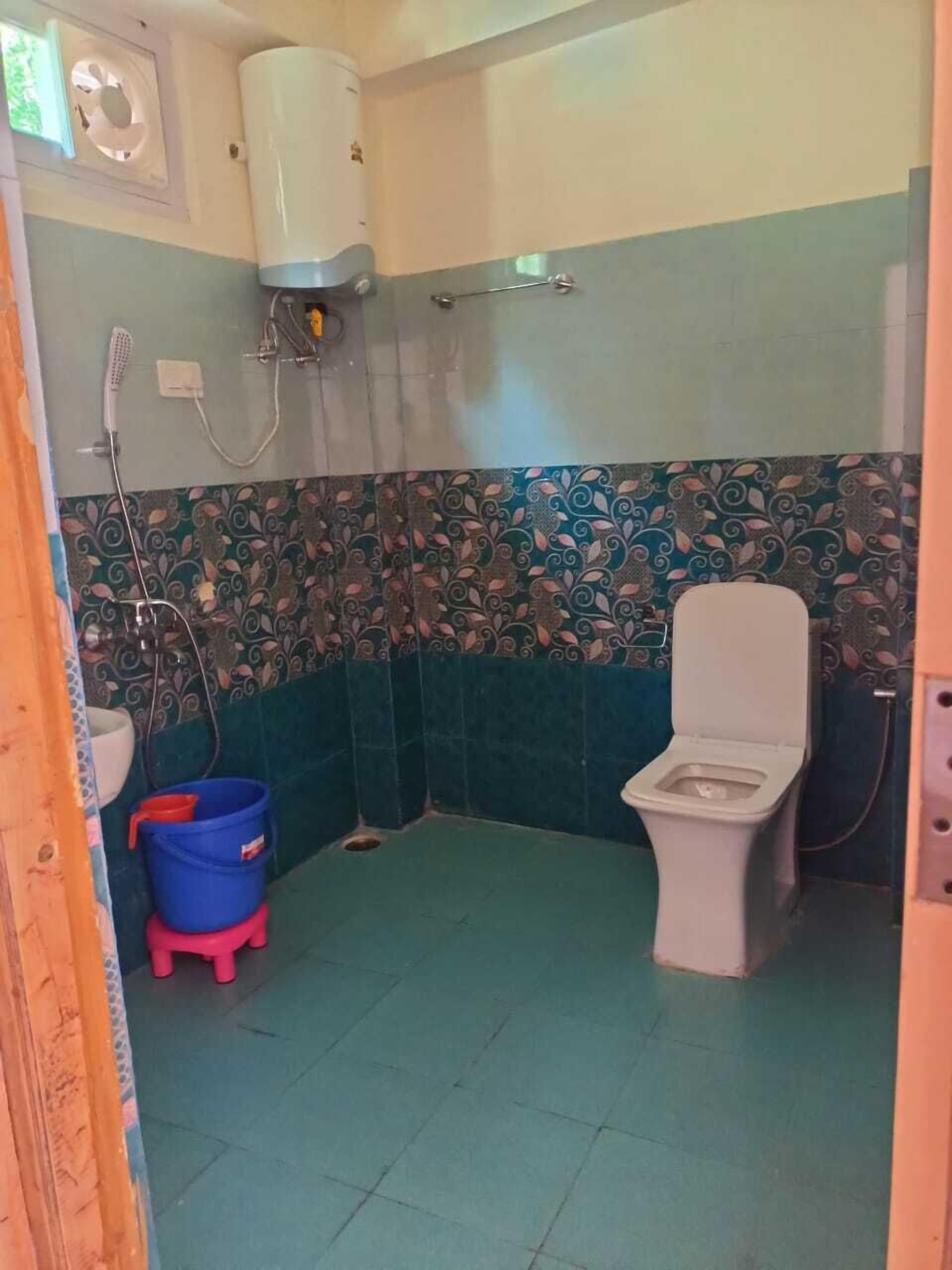 Ein kleines Badezimmer mit Toilette, Dusche und einem blauen Eimer.