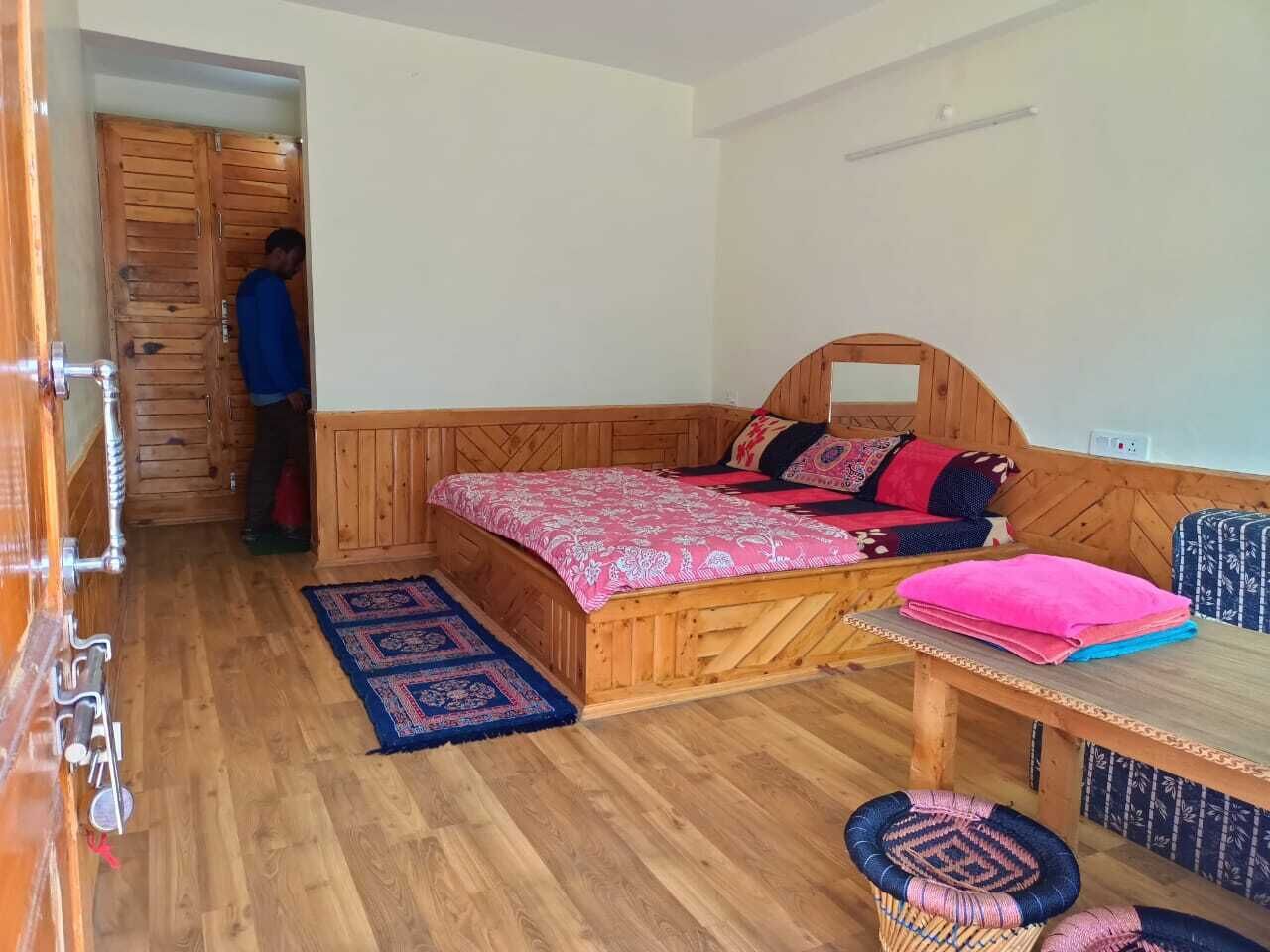 Una habitación de madera con una cama, una mesa y un banco.