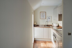 A kitchen with white cabinets, a wooden countertop, a sink, and a toaster. There are two framed signs on the wall. - Charming Central Mews Home with Secure Parking (Edinburgh)