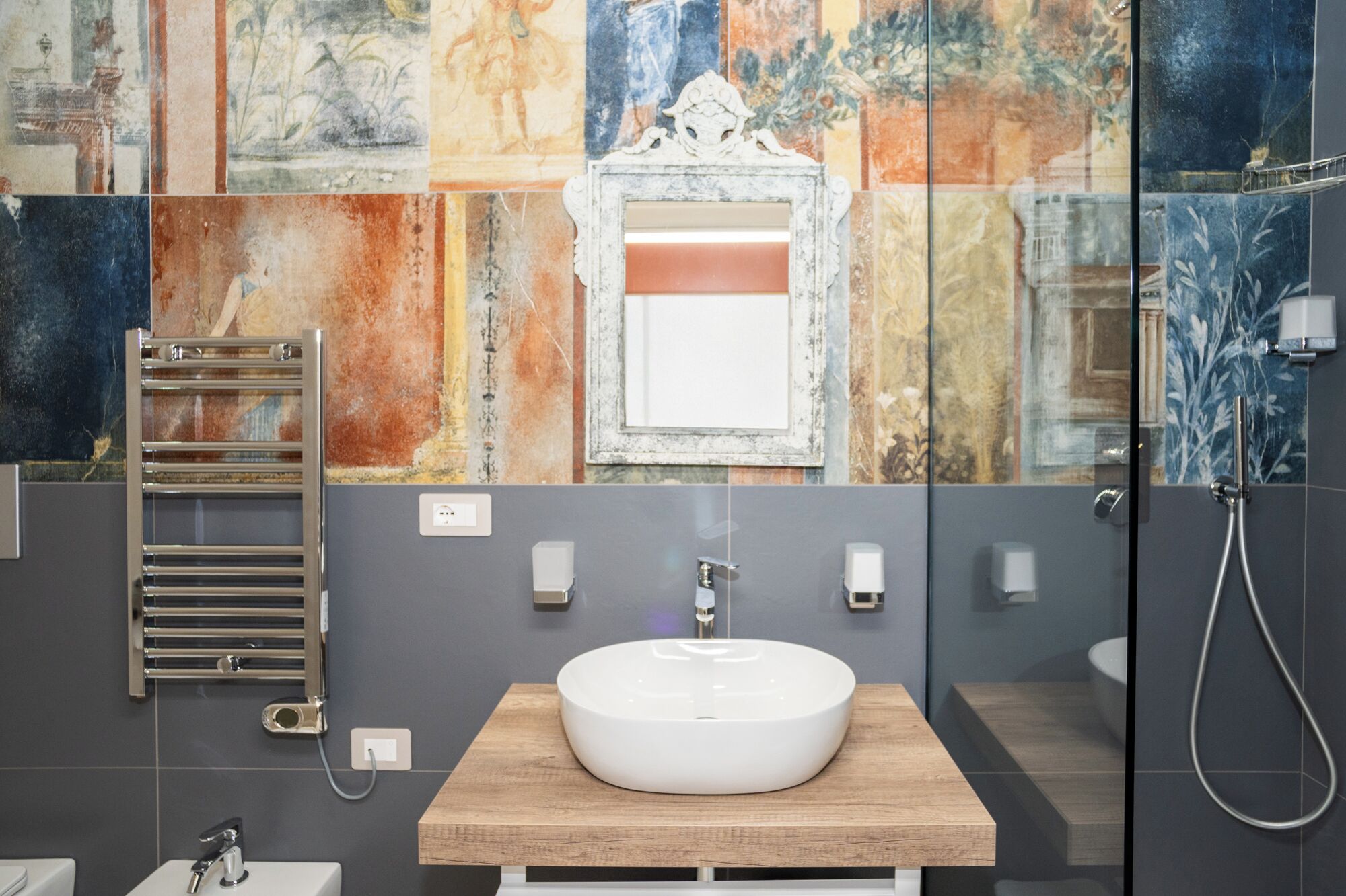 A modern bathroom with a central sink, a towel rack, and a shower.