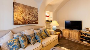 Un salon confortable avec un canapé, un téléviseur et un tableau accroché au mur.