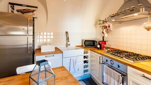 Une cuisine moderne dotée d’appareils électroménagers en acier inoxydable, d’un plan de travail en bois et d’un revêtement mural en carreaux.