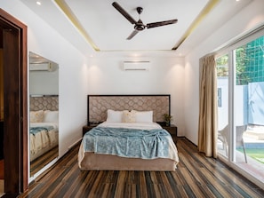 A modern bedroom with a large bed, a ceiling fan, and a view of the outdoors. - Dancenter Avanora Villa (Arpora)