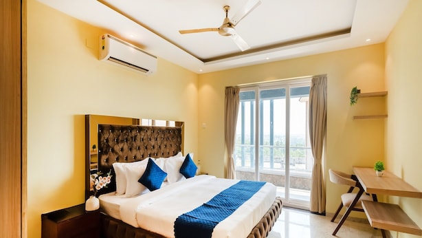 A bedroom with a large bed, a ceiling fan, an air conditioning unit, a desk, and a view of the outdoors. - Dancenter Avanora Villa (Arpora)
