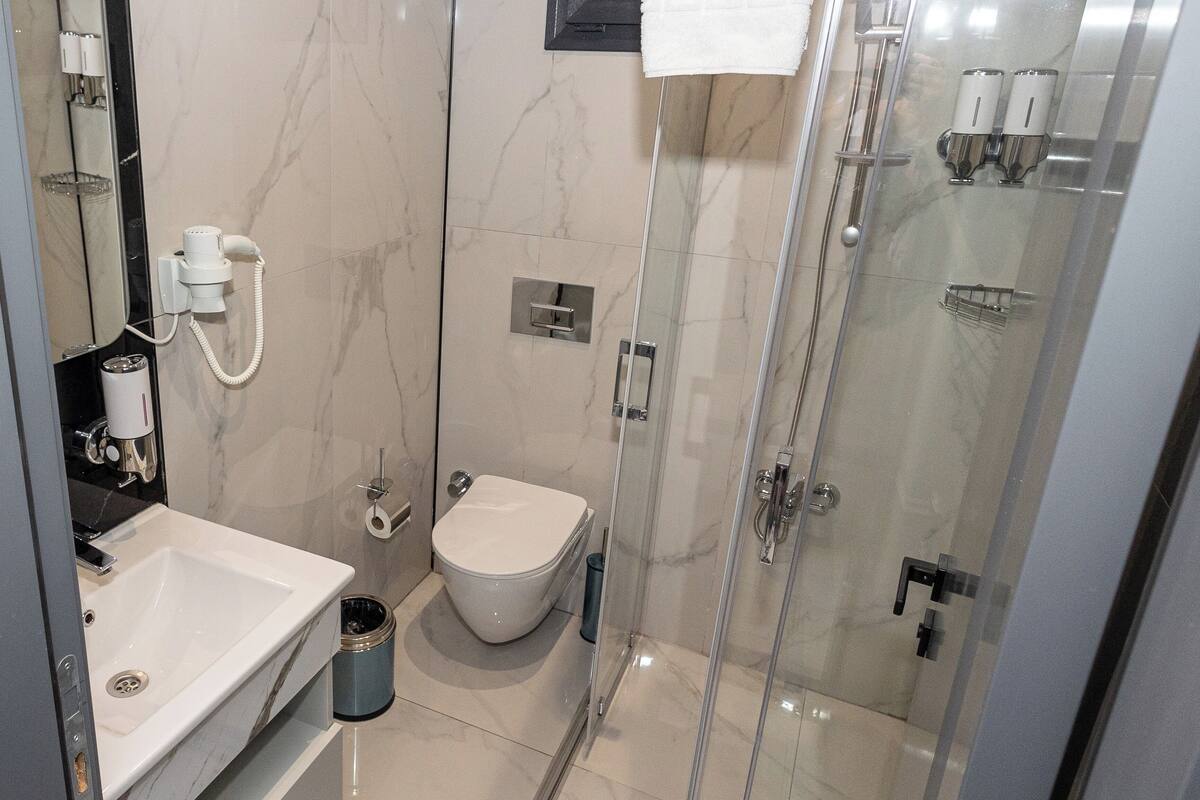A modern bathroom with a glass-enclosed shower, a white toilet, and a sink with a mirror.