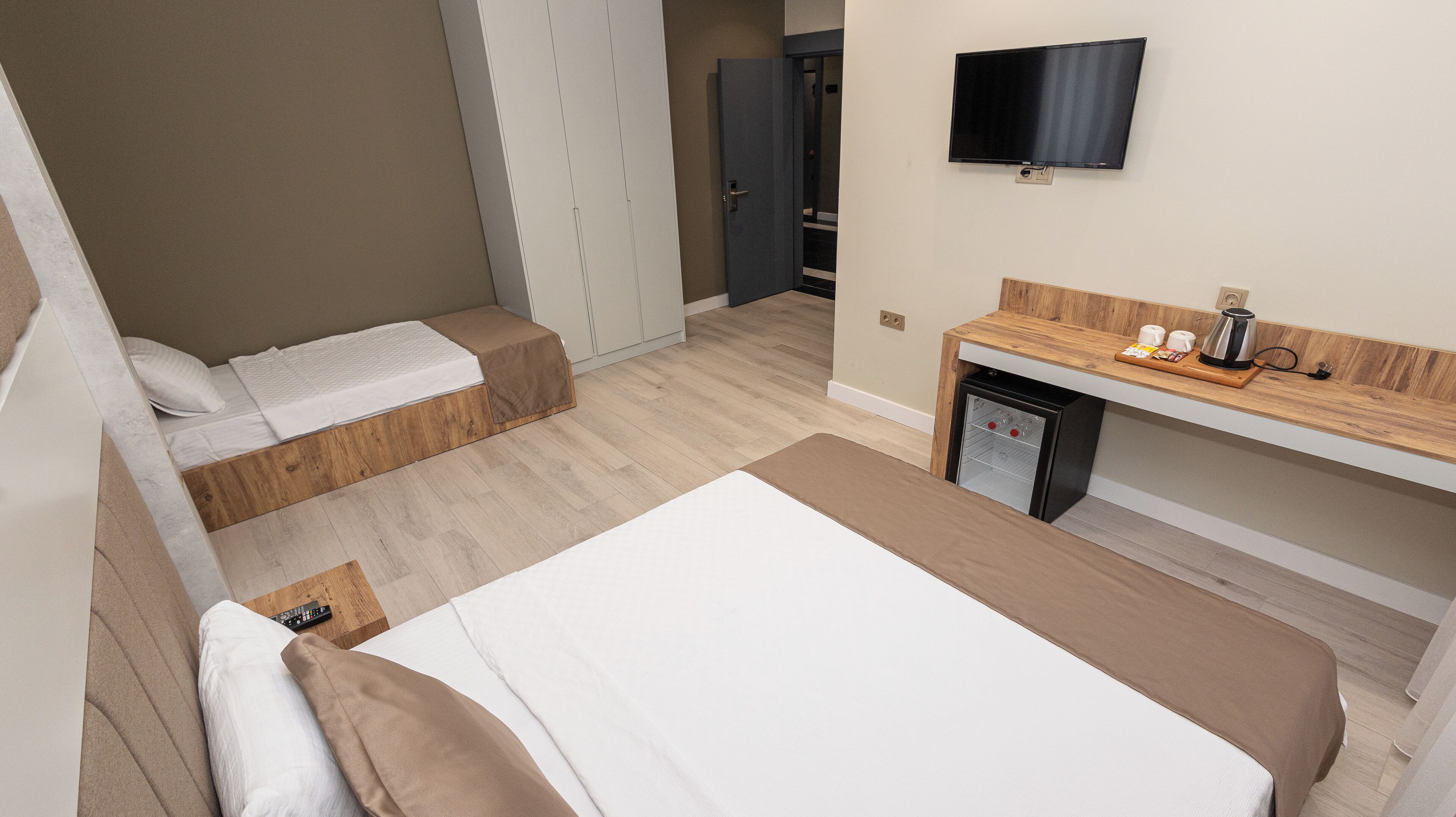 A hotel room with two beds, a TV, a coffee machine, and a mini-fridge.