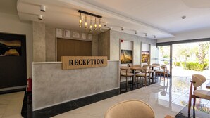 A reception area with a wooden sign, framed certificates, and a modern light fixture. - HOLMİ OTEL (Taşucu)
