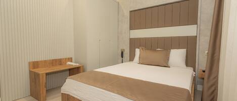A modern bedroom with a large bed, a wooden bench, and a telephone on the wall.