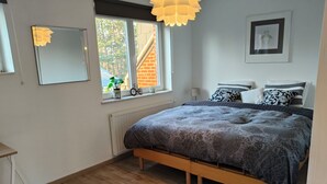 Un dormitorio con cama, ventana con vistas, radiador y espejo.