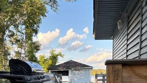 A wooden deck with a grill and a small shed. - Beautiful Riverfront House (Campbellford)