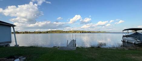 A lakeside view with a dock, a small shed, and a tent.