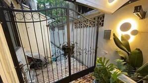 A gated entrance with a wrought iron gate, a wooden deck, and potted plants.