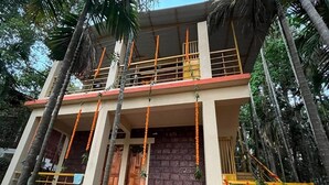 A two-story building with a balcony, a brick wall entrance, and a staircase with railings. - Green Breeze Resort (Dapoli)