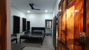A bedroom with a bed, a desk, a chair, a ceiling fan, and a wardrobe. - Green Breeze Resort (Dapoli)