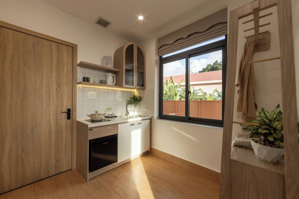 Una cucina compatta con mobili in legno, forno integrato e una finestra vista verde.
