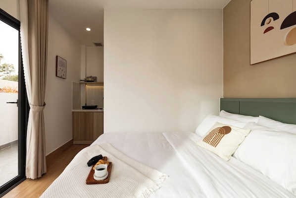 Ett hotellrum med en säng, ett brickbord med frukost, en kaffekopp och utsikt över omgivningarna.