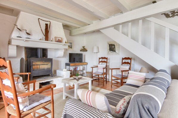 A cozy living room with a fireplace, wooden furniture, and a staircase.