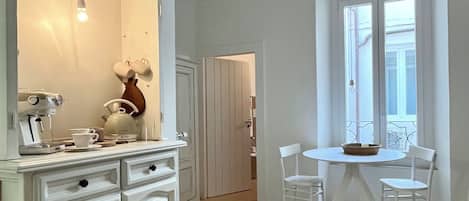 A room with a white cabinet, a table with two chairs, a window with a view, and a ceiling with exposed beams.