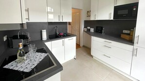 Una cocina moderna con armarios blancos, encimera negra y microondas.