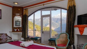 Habitación de hotel con cama, una silla, una mesita y televisión.