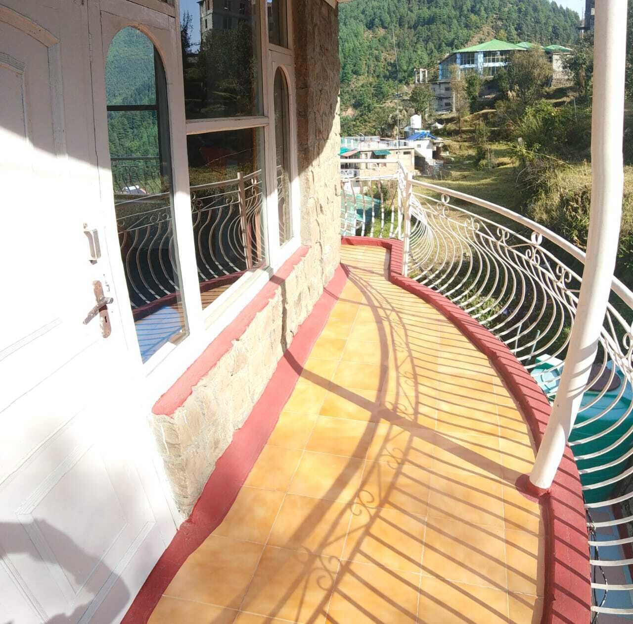 A balcony with a curved railing, a tiled floor, and a view of a mountainous landscape.