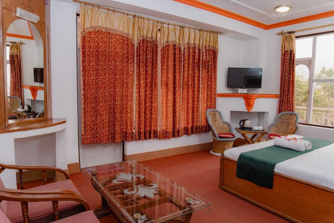 A hotel room with a bed, a TV, a desk with a chair, and a small table.