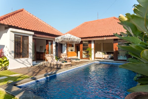 A modern house with a swimming pool, two lounge chairs, and a covered outdoor seating area. - Madeira Casa Canggu Bali (Canggu)