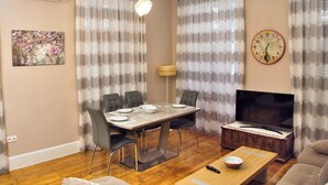 A dining area with a table set for four, a television, and a sofa. - Ideally Situated Corfu Old Town Family Retreat (Kerkira)
