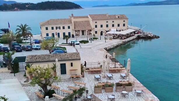 A coastal town with a waterfront promenade, outdoor seating areas, and a building with multiple windows. - Ideally Situated Corfu Old Town Family Retreat (Kerkira)