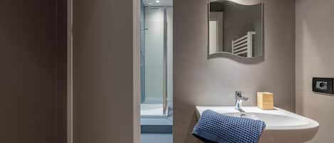 A modern bathroom with a white sink, a mirror, and a towel rack.