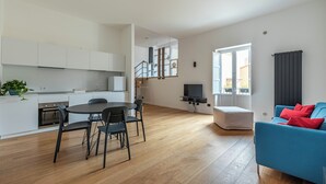 Een modern appartement met keuken, eetgedeelte, woonkamer en een trap naar een bovenverdieping.
