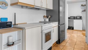 Eine moderne Küche mit weißen Schränken, einem Edelstahl-Kühlschrank, einem eingebauten Backofen und einer Mikrowelle.