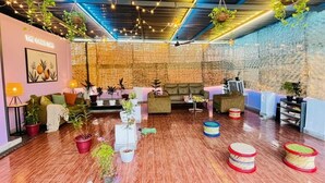 Un espace salon accueillant, avec un mur en briques, des plantes suspendues et différents types de sièges.