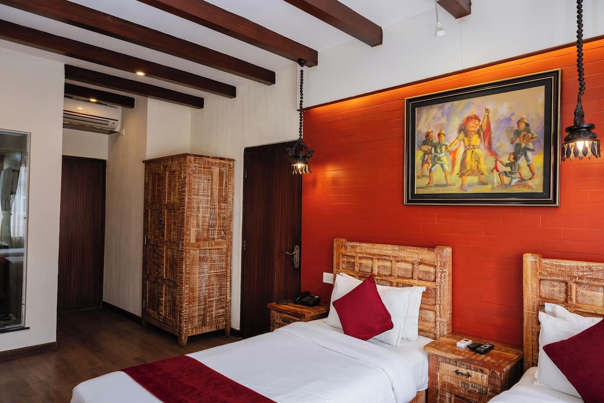 Een hotelkamer met een groot bed, twee nachtkastjes, een rieten kast en een schilderij aan de muur.