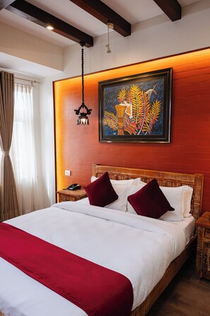 Un lit bien fait, avec une literie blanche et rouge, une tête de lit en bois et un mur d’accent rouge.
