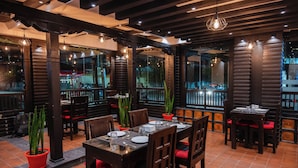 An indoor dining area with wooden tables and chairs, potted plants, and hanging pendant lights. - Evara Boutique Hotel (Kathmandu)