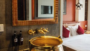 A bathroom with a large mirror, a gold sink, and a wooden cabinet. - Evara Boutique Hotel (Kathmandu)