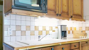 Una cocina con armarios de madera, microondas, fregadero y cafetera.