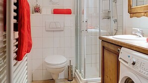 Un baño con inodoro, ducha y lavadora.