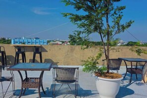 Outdoor seating with tables and chairs, a potted plant, and a view of the city skyline. - ONEWAY GUEST HOUSE BKK (Bangkok)