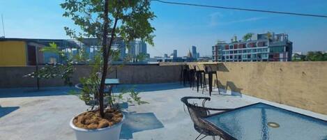 A rooftop terrace with a small tree, a pool, and a seating area.