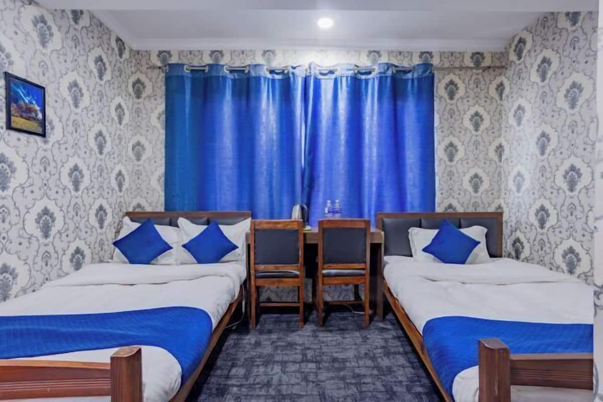 A hotel room with two single beds, a desk, and a chair.