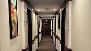 Un couloir d’hôtel avec des revêtements de sol en moquette, des boiseries et des portes de part et d’autre.