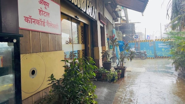 A hotel named 'CONCORD GALAXY' with a signboard in a local language, potted plants, and a wet pavement indicating recent rain. - Aboo's Hotel Concord Galaxy by Zuzu (Mumbai)