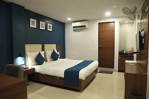 Camera d'albergo moderna con un letto grande, comodini, una scrivania e un condizionatore d'aria.