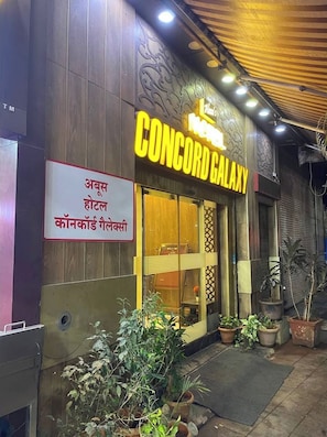 A hotel named 'CONCORD GALAXY' with a sign in Hindi, wooden paneling, and potted plants outside. - Aboo's Hotel Concord Galaxy by Zuzu (Mumbai)