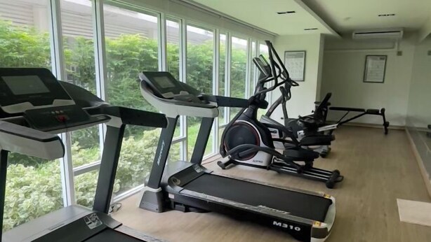 Un gimnasio con cintas de correr, elípticas y una bicicleta estática.