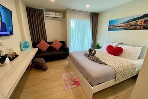 A hotel room with a bed, a sofa, a TV, and a painting on the wall. - Sunrise good view @ East Ville Bangsaen (Chon Buri)