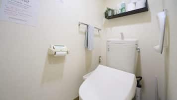 A bathroom with a toilet, a shelf with toiletries, and a paper sign on the wall.